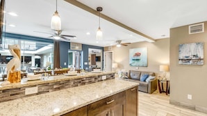 A modern kitchen with granite countertops, dark cabinetry, and pendant lighting.