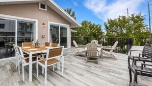 A covered patio with a dining table and chairs, a grill, and a poolside area with lounge chairs.
