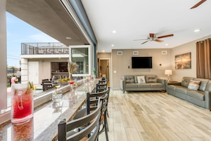 A spacious living area with a dining table, sofas, and a TV.