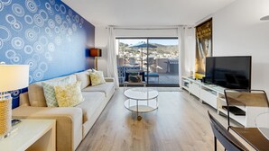 A modern living room with a sofa, coffee table, TV, and a balcony with a view.