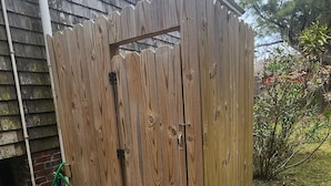 Un recinto in legno con un cancello, un pontile di legno e un prato con un cespuglio.