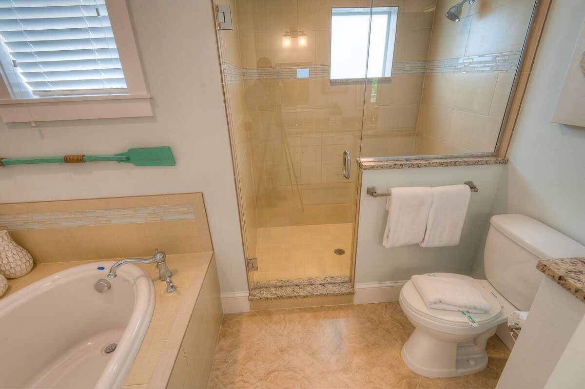 Et badeværelse med badekar, toilet og brusekabine.
