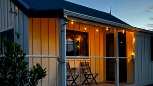 A building with a porch, two chairs, and string lights.