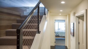 Un escalier avec une rampe en métal menant à une chambre à coucher qui contient un lit et une fenêtre.