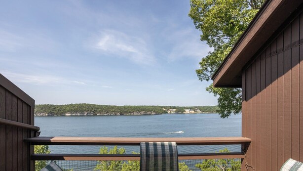 Una terraza con vista a un lago, una silla y una mesa.