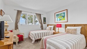 Un dormitorio con dos camas, televisión, escritorio y ventana con cortinas.