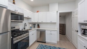 Una cocina moderna con armarios blancos, electrodomésticos de acero inoxidable y un tapete azul estampado.