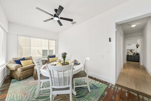 A dining area with a round table, white chairs, and a ceiling fan. - Bright Beach Cottage w/ Patio l  Steps to the Beach & Restaurants l  Pet-Friendly (Clearwater)