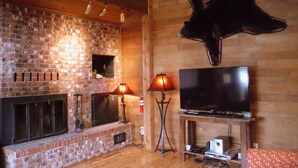 Ein gemütliches Wohnzimmer mit Kamin aus Backstein, einem wandmontierten Fernseher und einer Lederwanddekoration.