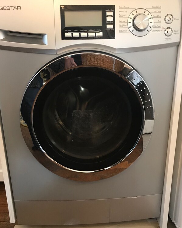 A front view of a front-loading washing machine with a control panel above the door.