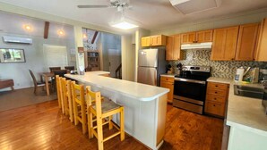 Une cuisine moderne avec des meubles en bois, un réfrigérateur en acier inoxydable, un four encastré et un grand îlot central doté de tabourets de bar.