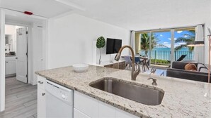 A modern kitchen with a granite countertop, stainless steel sink, and white cabinetry.