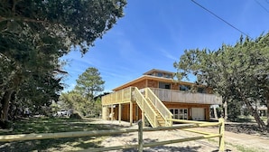 A two-story house with a balcony, surrounded by trees. - Jonathan Livingston Seagull:  Dog friendly single story home. (Ocracoke)