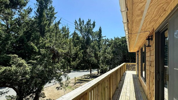 A wooden deck with a railing, overlooking a forested area. - Jonathan Livingston Seagull:  Dog friendly single story home. (Ocracoke)
