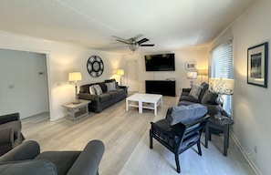 A living room with a sofa, coffee table, TV, and a ceiling fan.