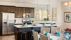 A modern kitchen with dark wooden cabinets, stainless steel appliances, and a central island with blue accents. - PVZ 33|Steps to Pools *Misters* Pool/Mtn PatioView (Santa Clara)