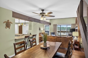 A dining area with a wooden table, chairs, a ceiling fan, and a view of the outdoors.