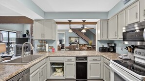 Una cocina con encimeras de granito, electrodomésticos de acero inoxidable y armarios de color gris claro.