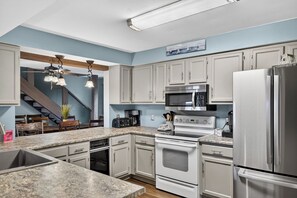 A modern kitchen with granite countertops, stainless steel appliances, and light gray cabinetry.