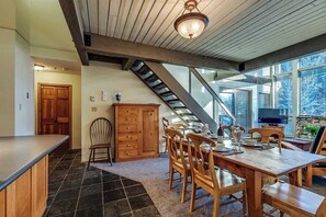 Ein Essbereich mit Holztisch und Stühlen, einer Treppe und einem großen Fenster mit Blick.