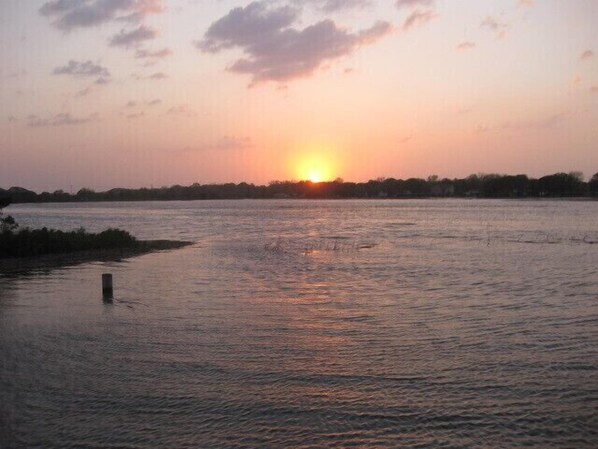 Ein Sonnenuntergang über einem ruhigen Fluss mit einer entfernten Baumlinie.