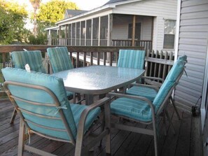 Eine überdachte Terrasse mit einem runden Tisch und sechs Stühlen.