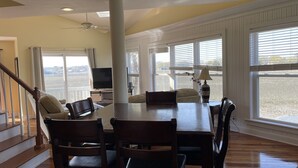 A dining area with a large table, chairs, a television, and a lamp. - Folly Beach Riverfront Apt with dock, private boat ramp kayaks and bikes (Folly Beach)