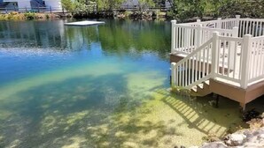 A clear pond with a wooden deck and steps leading into the water. - NEW! Casa Azul - NO HIDDEN FEES! Golf Cart, 2 Kings, Pool, Beach, Tennis, Kayaks (Key Largo)