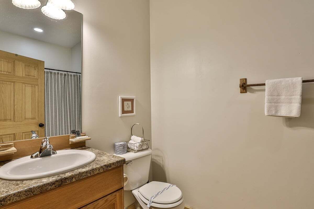 Une salle de bain équipée d’un lavabo, d’un miroir, de toilettes et d’un porte-serviettes.