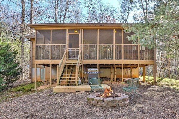 A two-story cabin with a deck, a fire pit, and outdoor seating.