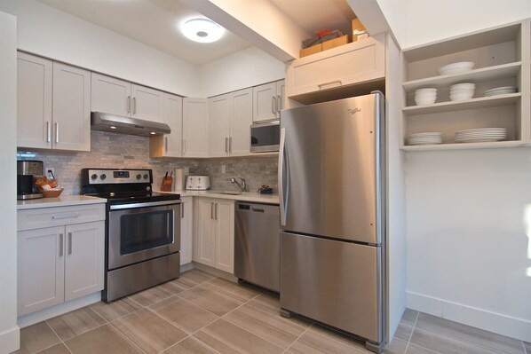 A modern kitchen with stainless steel appliances, white cabinetry, and a built-in oven.
