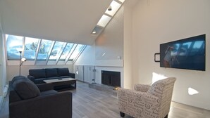 Una sala de estar moderna con sofá, sillón y televisor de pantalla plana montado en la pared.