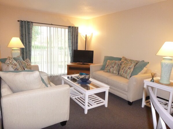 A living room with a sofa, armchair, coffee table, and a television on a stand. - Shorewalk rental By Owner/Condo 2bed/2bath/IMG Academy /Anna Maria Island (Bradenton)