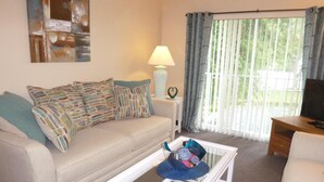 Un salon avec un canapé, une table basse, une lampe et un téléviseur.