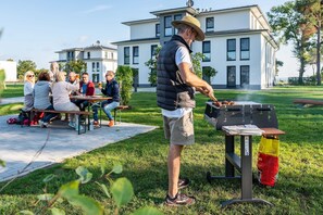 A group of people dining outdoors with a barbecue grill.