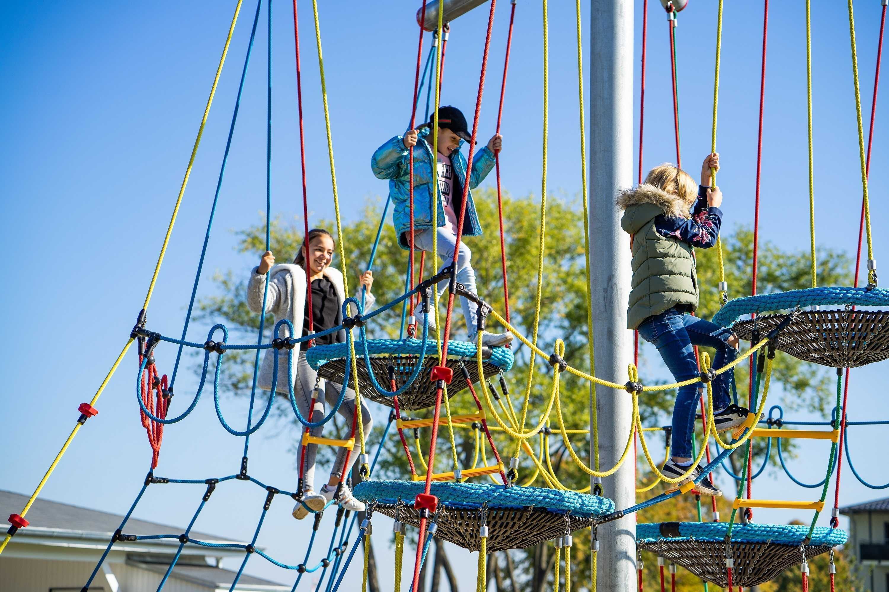 Un parque infantil con un puente de cuerda y zonas de escalada con redes.