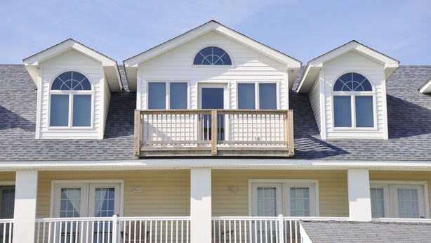 Een huis met twee verdiepingen, een balkon, een veranda en een garage.