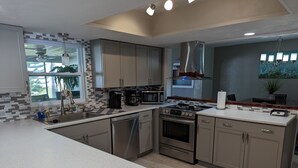 A modern kitchen with a central island, stainless steel appliances, and a large window providing natural light. - Stay 5 Nights, Get 1 Night Free - 4 BR home in quiet setting close to everything (Port Orange)