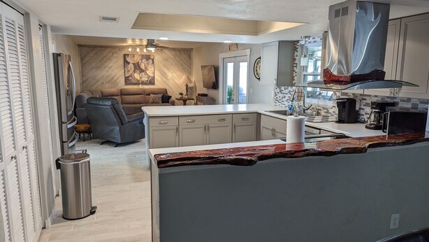 A modern kitchen with a central island, built-in cabinets, and a stainless steel range hood. - Stay 5 Nights, Get 1 Night Free - 4 BR home in quiet setting close to everything (Port Orange)