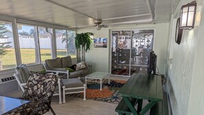 A covered patio area with a sofa, chairs, a table, and a bench. - Stay 5 Nights, Get 1 Night Free - 4 BR home in quiet setting close to everything (Port Orange)