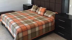 Un dormitorio con cama, mesitas de noche, ventilador de techo y aire acondicionado.