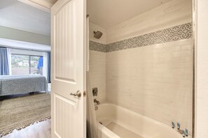 Ein Badezimmer mit Badewanne, Dusche und einem fensterbepflanzten Fenster.