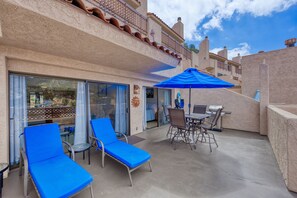 Ein Balkon mit blauen Lounge-Stühlen, einem Tisch mit Stühlen und einem Grill.