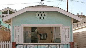 A small, single-story house with a light blue exterior, a large window, and a white picket fence. - 319CE: Budget-friendly Cottage, 2.5 Blocks to Beach and Shops + WIFI (Avalon)