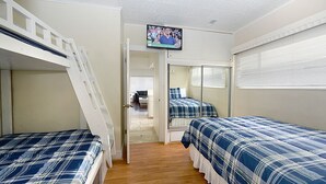 A bedroom with bunk beds, a television mounted on the wall, and a door leading to another room. - 319CE: Budget-friendly Cottage, 2.5 Blocks to Beach and Shops + WIFI (Avalon)