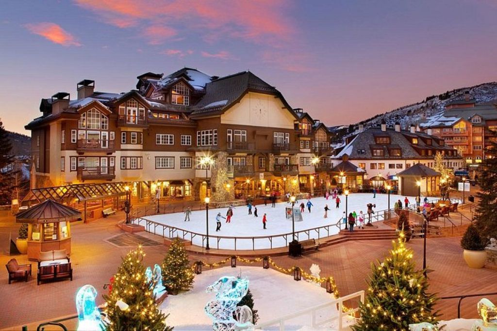 A hotel with a large central courtyard, a snow-covered hill in the background, and a well-lit exterior.