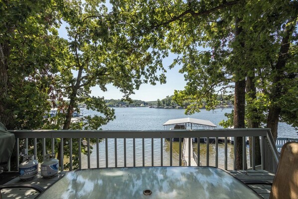 A lakeside deck with a view of the water, trees, and a covered area.