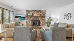 Ein Wohnzimmer mit Kamin aus Stein, zwei Sofas, einem Fernseher und einer Pflanze.