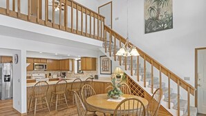 Eine geräumige Küche mit Holzausstattung, ein Essbereich mit rundem Tisch und Stühlen sowie eine Treppe mit Holzbalken.