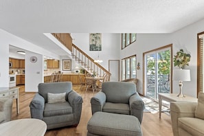 A spacious living room with a staircase, dining area, and kitchen.